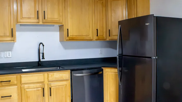 Remodeled kitchen in Woodside Creek Village 5-bedroom Bountiful house with wood cabinets, black refrigerator, and dishwasher.