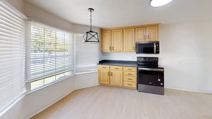 Bright kitchen nook with bay windows, wood cabinetry, and stainless steel appliances in the Woodside Creek Village home.