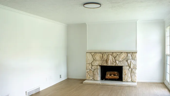 Living room with stone fireplace and wood-style floors in the 5-bedroom Woodside Creek Village house.