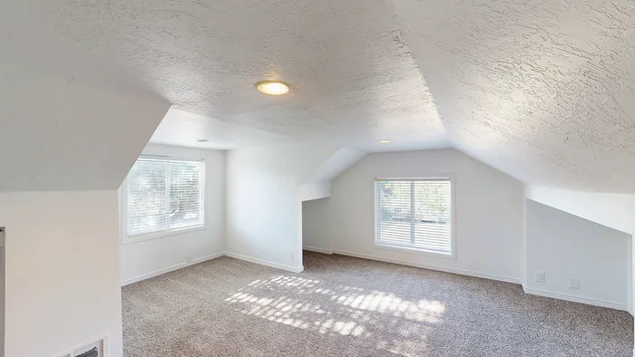 Loft area with carpet flooring and large windows in the 5-bedroom Woodside Creek Village stand-alone house.