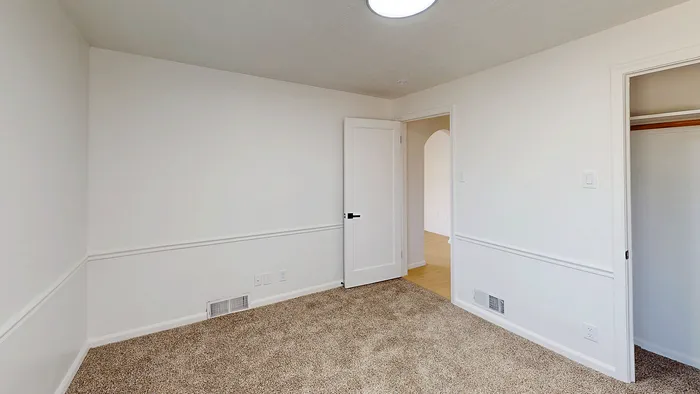 Main floor bedroom with carpet flooring, closet, and neutral finishes in the Woodside Creek Village 5-bedroom home.